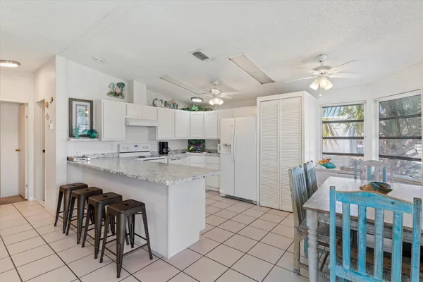 a kitchen with stainless steel appliances kitchen island granite countertop a table chairs and a refrigerator
