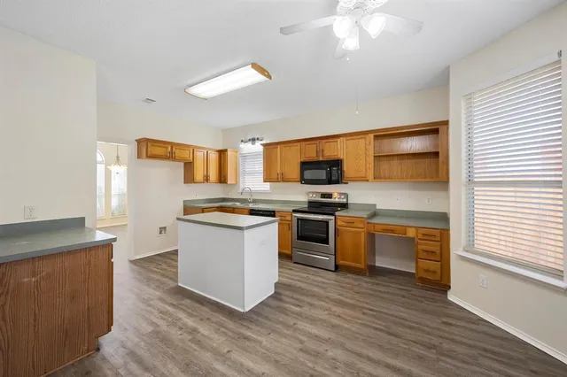 a kitchen with stainless steel appliances kitchen island granite countertop a stove a sink and a microwave