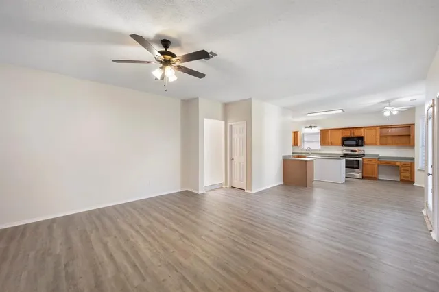 a view of a livingroom with a ceiling fan and kitchen space