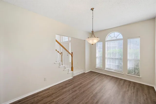 a view of a room with wooden floor chandelier and windows