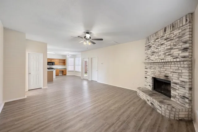 a view of an empty room with kitchen and fireplace