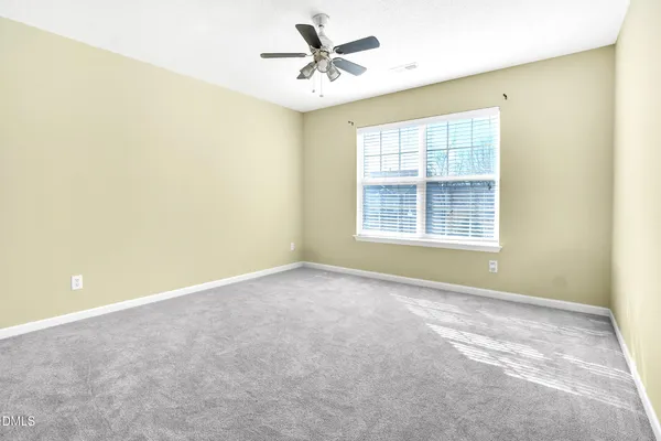 an empty room with windows and ceiling fan