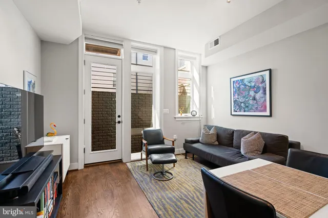 a living room with stainless steel appliances kitchen island granite countertop furniture and a wooden floor