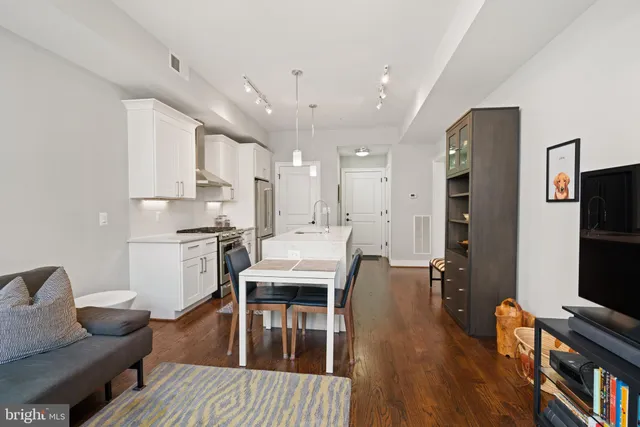 a open kitchen with stainless steel appliances granite countertop a stove refrigerator and a dining table with wooden floor