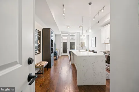 a kitchen with stainless steel appliances a refrigerator a stove a sink a dining table and chairs with wooden floor