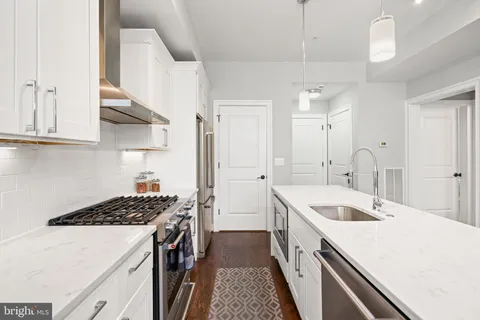 a kitchen with a sink a stove a refrigerator and white cabinets