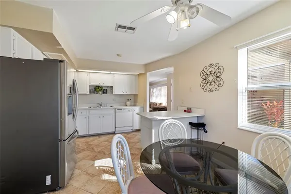 a kitchen with stainless steel appliances granite countertop a sink a stove a dining table and chairs with wooden floor