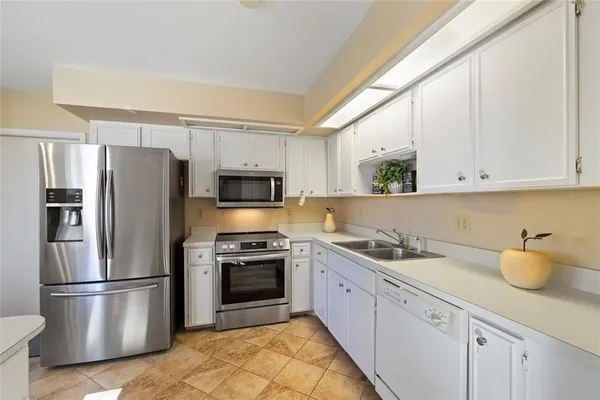 a kitchen with a sink a refrigerator and white cabinets