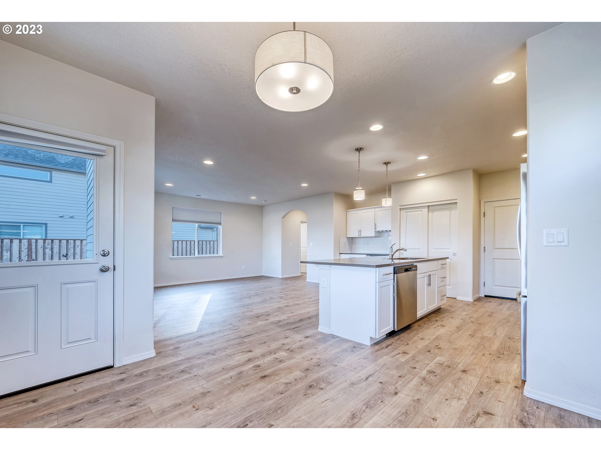1057 Laura Street Springfield, OR 97477 - Photo 11 of 39 a open kitchen with white cabinets a sink dishwasher a dining table and chairs with wooden floor