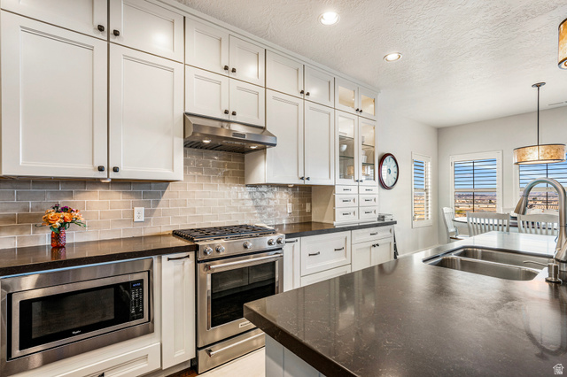 2311 South 1340 West St. George, UT 84770 - Photo 16 of 56 Kitchen featuring stainless steel appliances, decorative light fixtures, backsplash, dark stone counters, and a textured ceiling