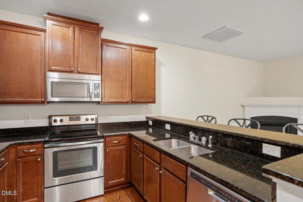 2306 Stoney Spring Drive Raleigh, NC 27610 - Photo 10 of 35 a kitchen with granite countertop a sink a stove and cabinets