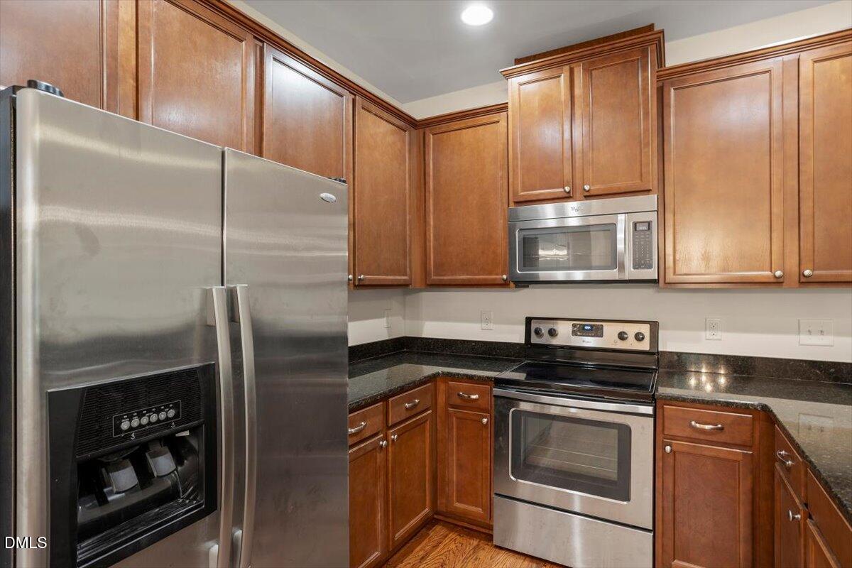 2306 Stoney Spring Drive Raleigh, NC 27610 - Photo 12 of 36 a kitchen with stainless steel appliances granite countertop a refrigerator a stove and a sink with wooden floor