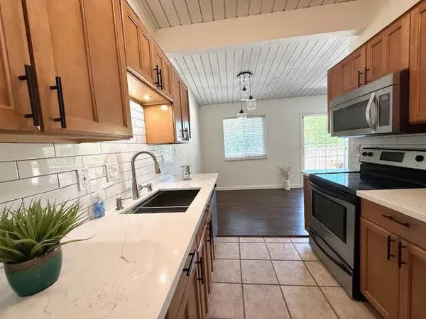 a kitchen with stainless steel appliances a sink a stove a microwave a sink a refrigerator and cabinets