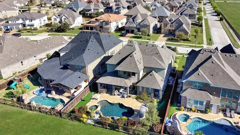 an aerial view of residential houses with outdoor space and parking