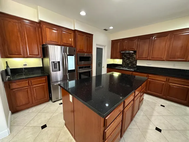 a kitchen with stainless steel appliances granite countertop a sink a stove and a refrigerator