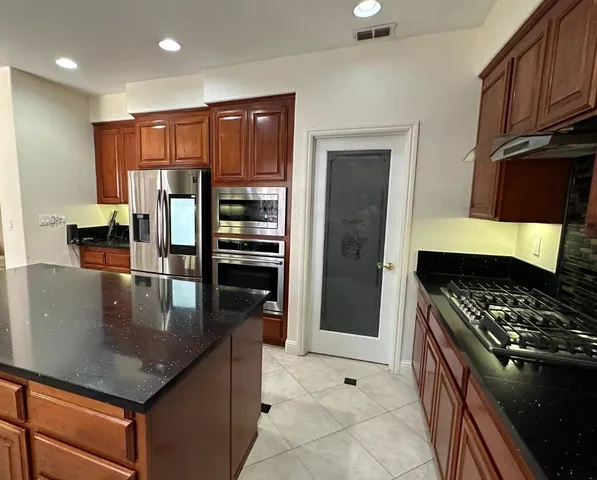 a kitchen with stainless steel appliances granite countertop a stove refrigerator and microwave