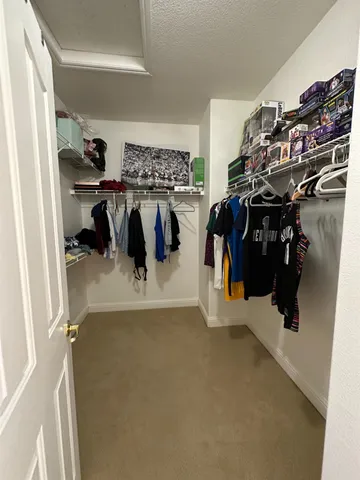 a view of walk in closet with clothes and shoes