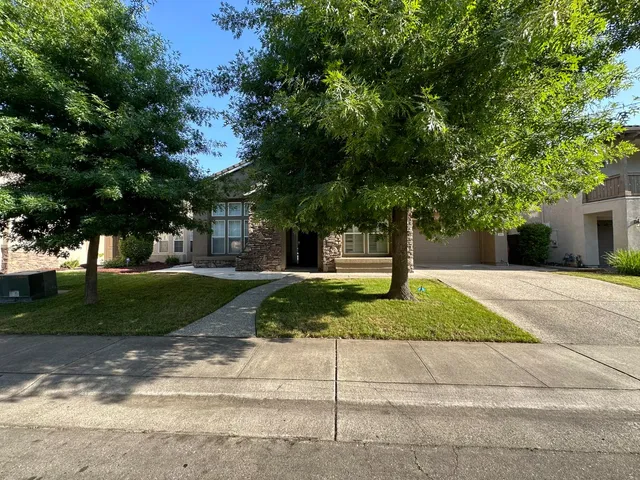 a front view of a house with a yard and tree s