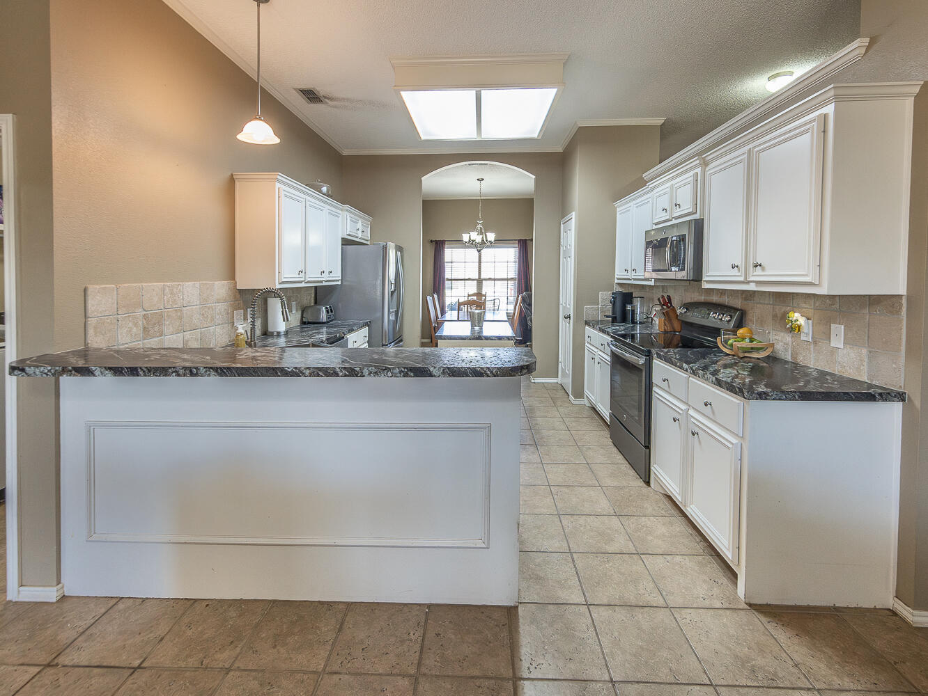 6901 9th Street Lubbock, TX 79416 - Photo 17 of 27 a large kitchen with granite countertop a stove a sink dishwasher and a refrigerator