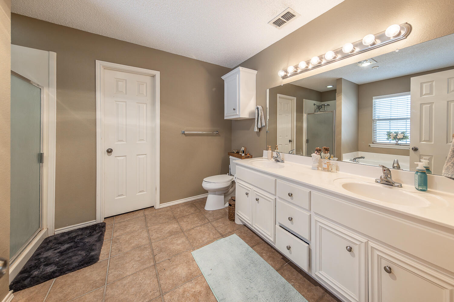 6901 9th Street Lubbock, TX 79416 - Photo 26 of 27 a spacious bathroom with a double vanity sink a mirror and a toilet