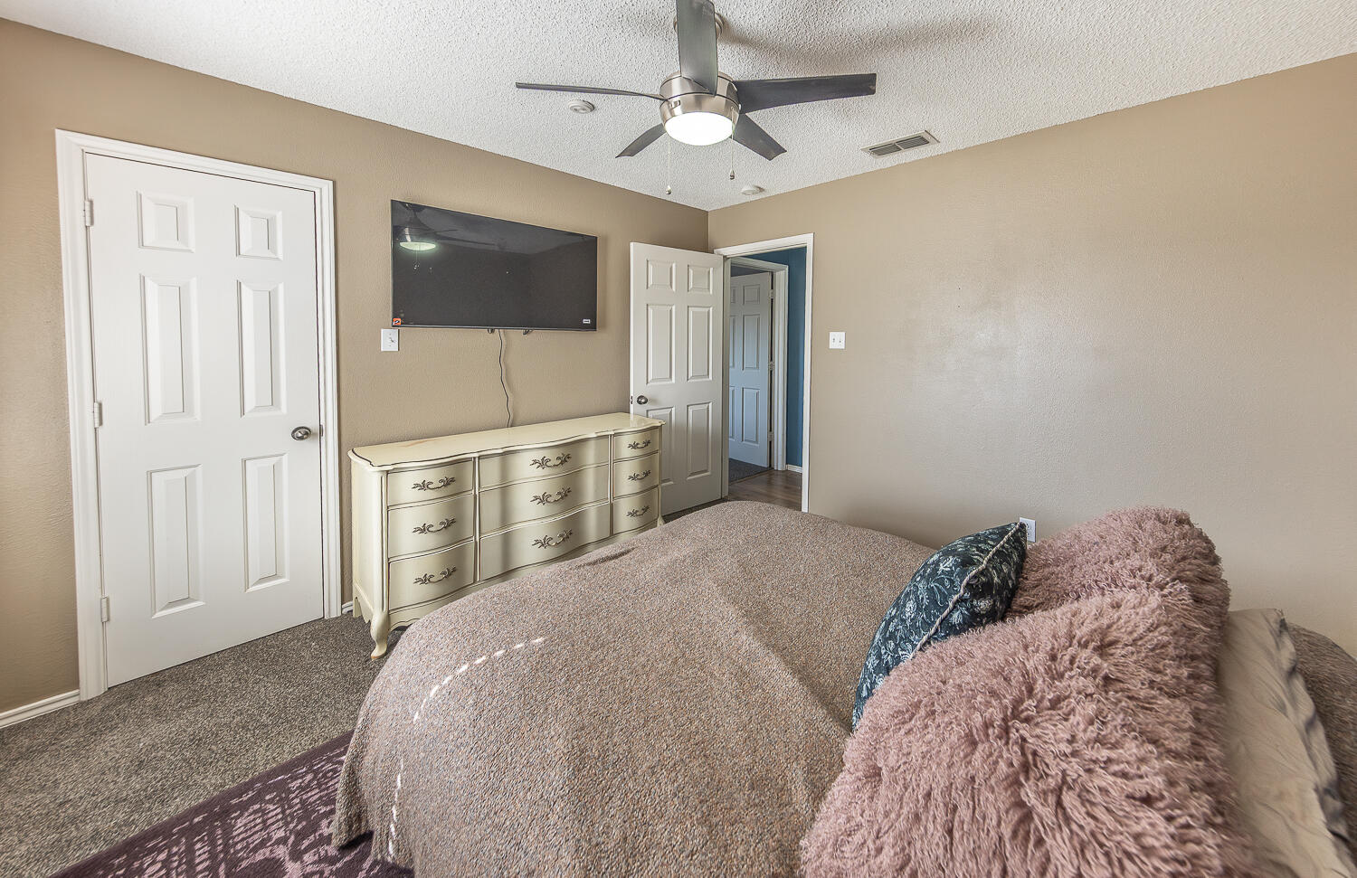 6901 9th Street Lubbock, TX 79416 - Photo 10 of 27 a spacious bedroom with a bed and a flat screen tv