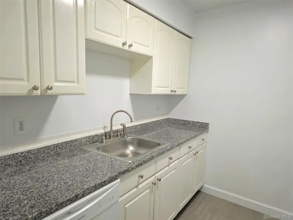 a kitchen with granite countertop white cabinets and a sink