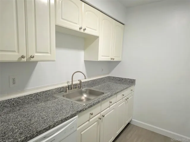 a kitchen with granite countertop white cabinets and a sink