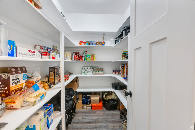 252 North Sunrise Rnch Drive Mapleton, UT 84664 - Photo 25 of 62 Walk-in pantry featuring white shelving, wood-finish flooring, and a solid panel door with dark hardware