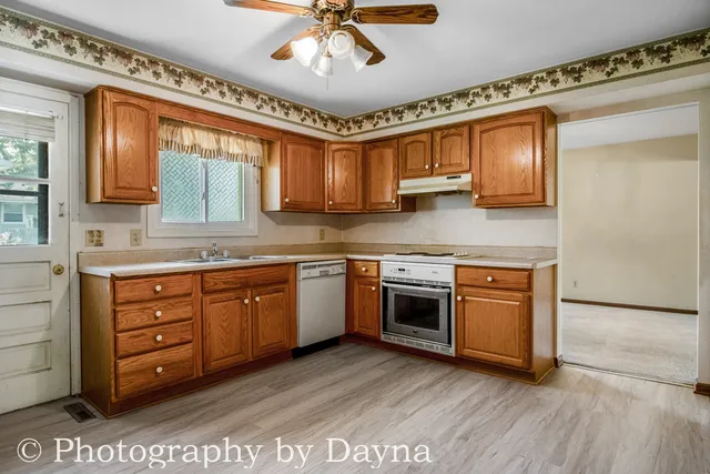 a kitchen with stainless steel appliances granite countertop a sink dishwasher stove and refrigerator with wooden floor
