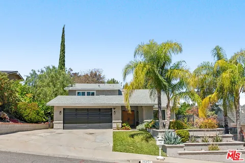 a front view of a house with a yard and palm trees