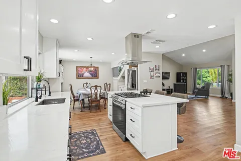 a living room with furniture and kitchen view with wooden floor
