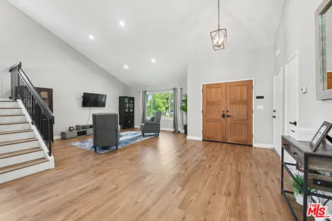 a living room with stainless steel appliances kitchen island granite countertop furniture and a wooden floor