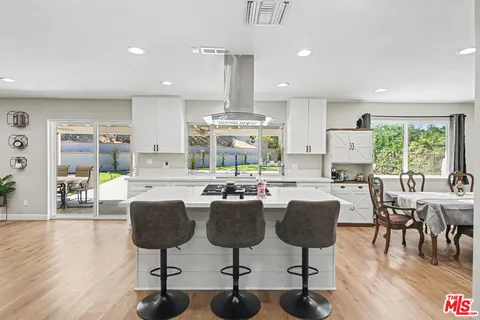 a kitchen with stainless steel appliances a dining table chairs and wooden floor