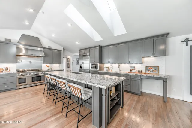 a kitchen with stainless steel appliances granite countertop a table chairs sink and cabinets
