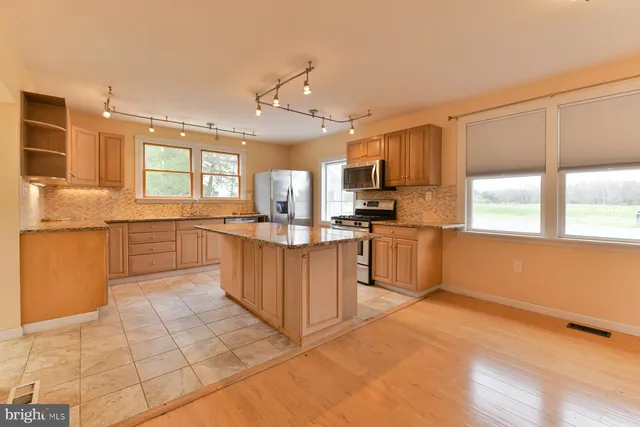 a large kitchen with cabinets a sink a window and stainless steel appliances