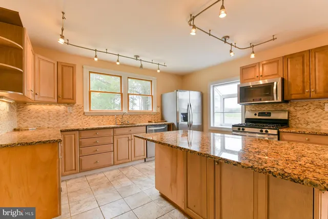 a kitchen with stainless steel appliances granite countertop a sink a stove counter space and cabinets