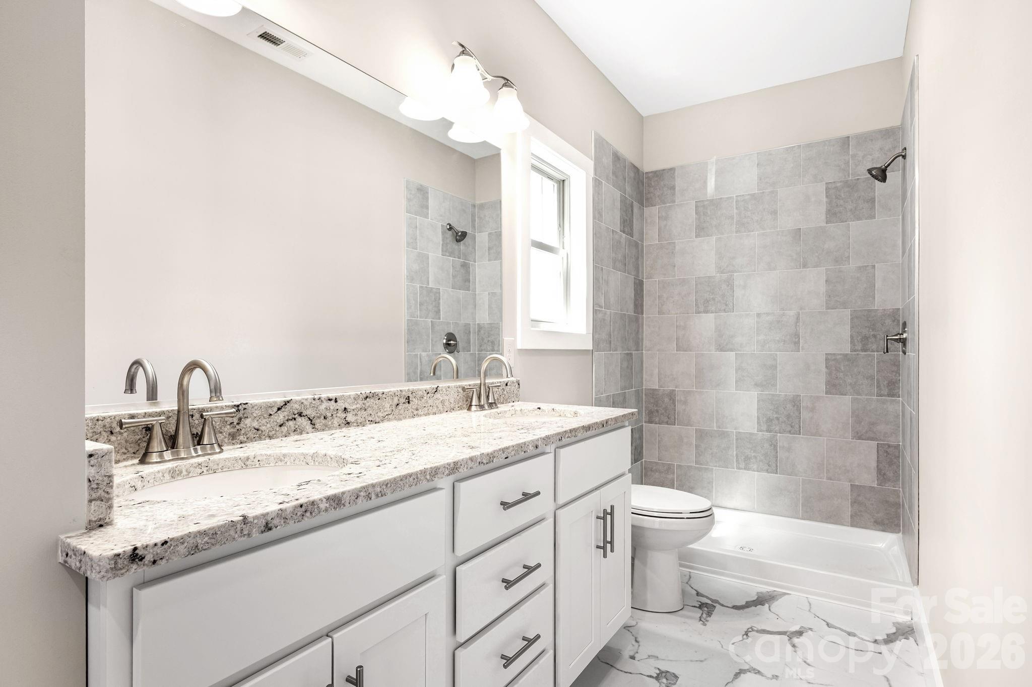 79 Wheeler Road Weaverville, NC 28787 - Photo 16 of 33 a bathroom with a granite countertop sink a toilet a mirror and shower