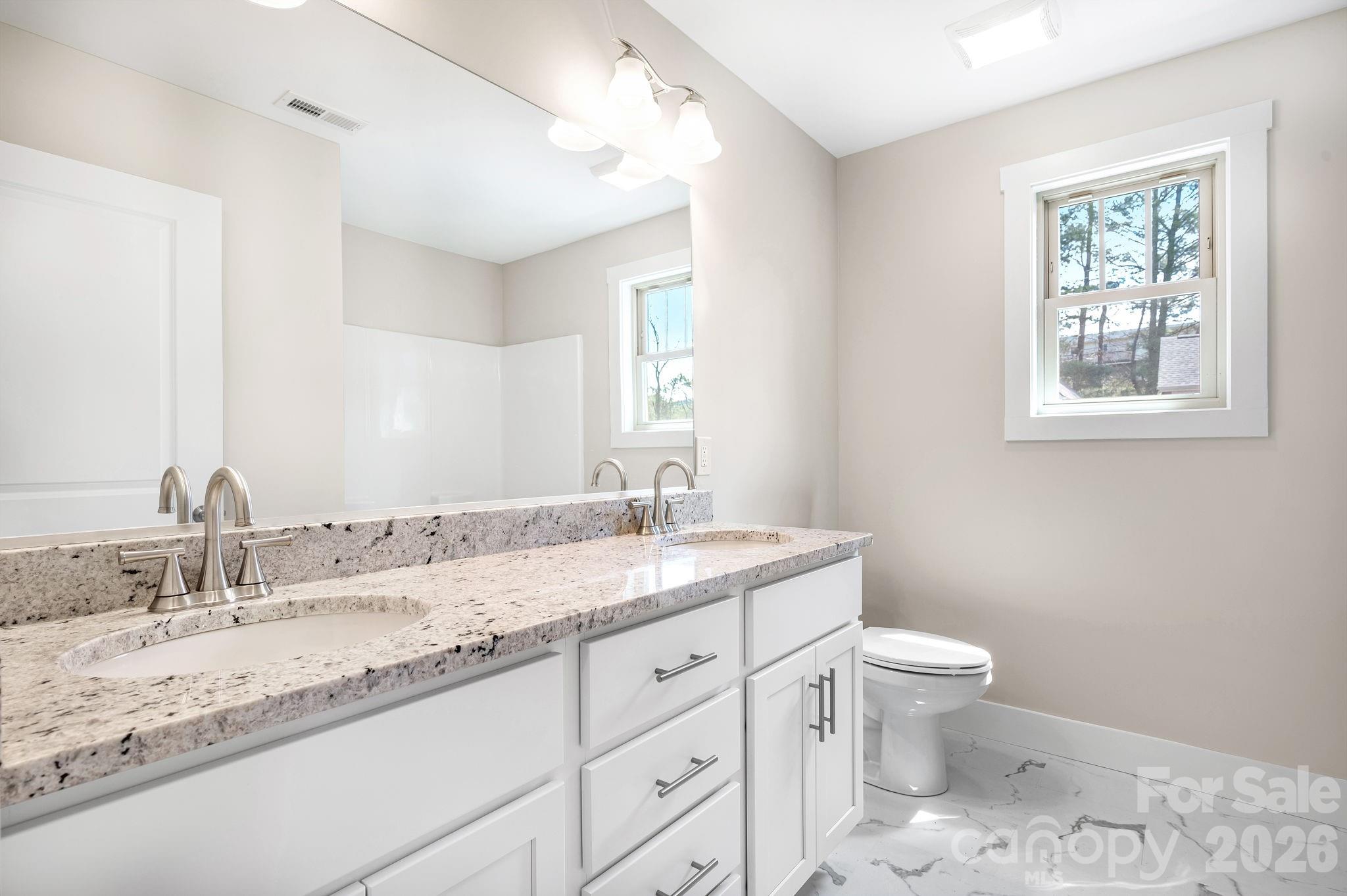 79 Wheeler Road Weaverville, NC 28787 - Photo 26 of 33 a bathroom with a granite countertop sink a toilet and a window