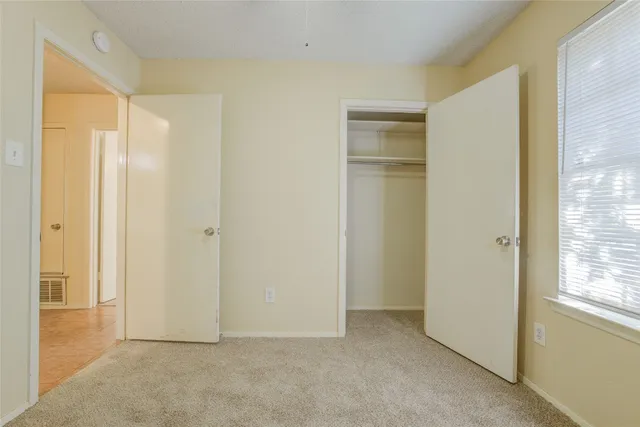 an empty room with windows and ceiling fan