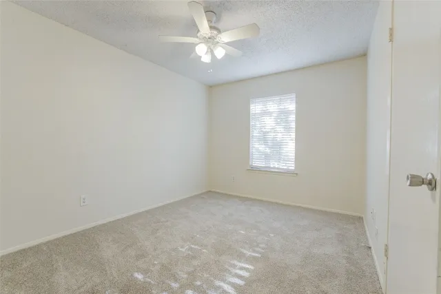 an empty room with a window and a fan