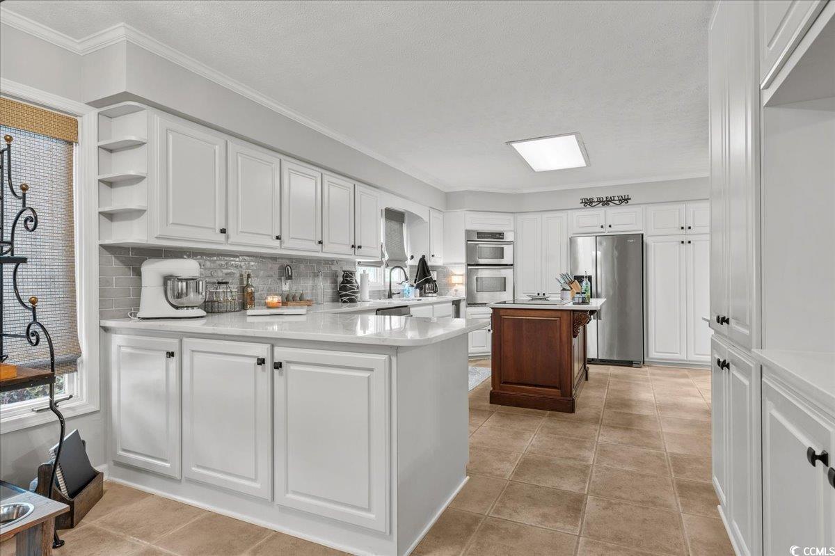 117 John Waites Court Georgetown, SC 29440 - Photo 15 of 40 Kitchen featuring white cabinetry, open shelves, appliances with stainless steel finishes, backsplash, and crown molding