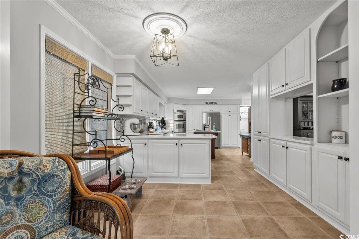 117 John Waites Court Georgetown, SC 29440 - Photo 16 of 40 Kitchen with open shelves, white cabinetry, a textured ceiling, a peninsula, and appliances with stainless steel finishes