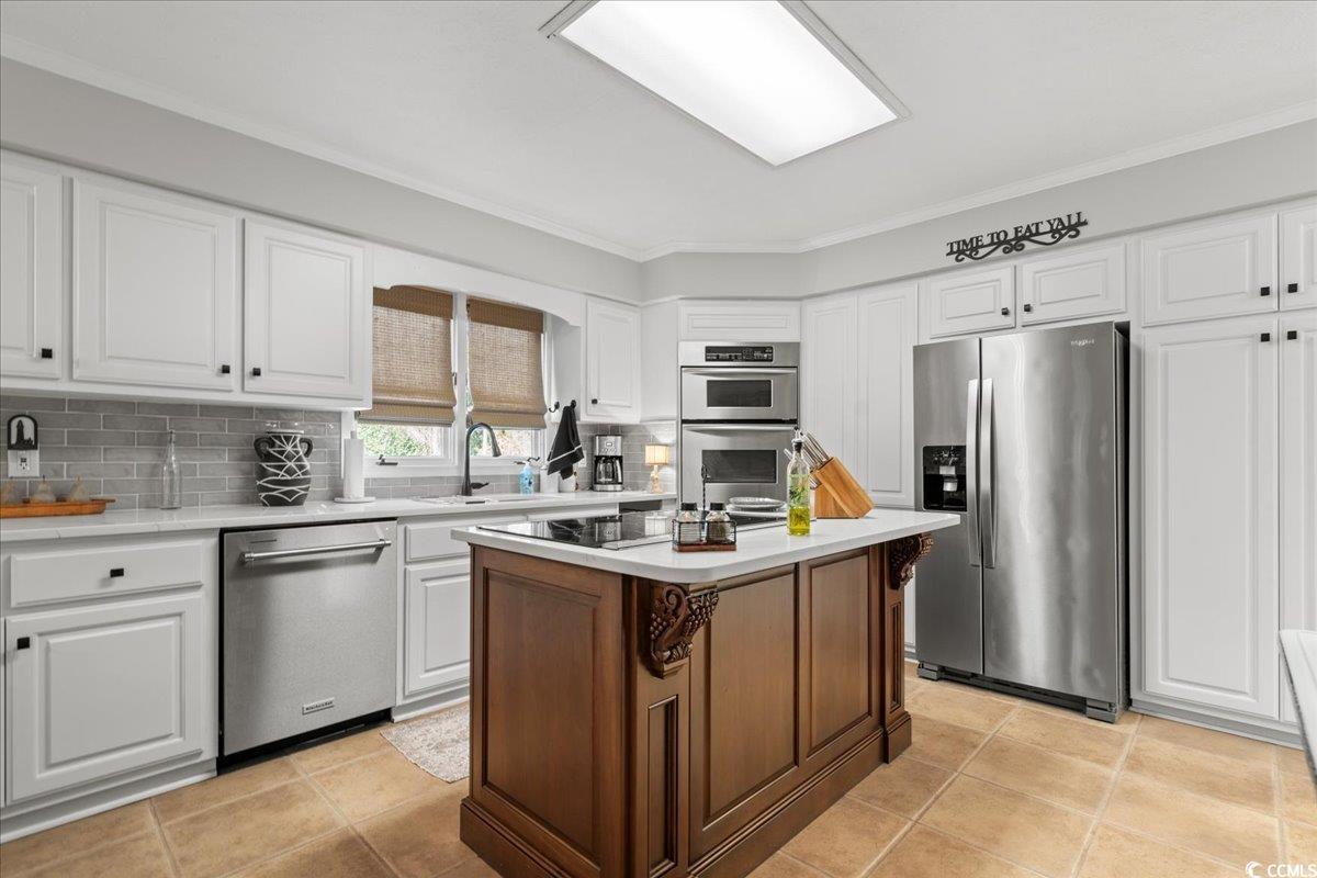 117 John Waites Court Georgetown, SC 29440 - Photo 17 of 40 Kitchen featuring appliances with stainless steel finishes, crown molding, white cabinetry, decorative backsplash, and light tile patterned floors