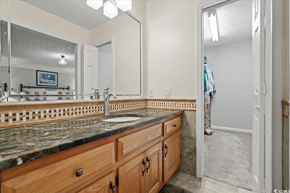 117 John Waites Court Georgetown, SC 29440 - Photo 27 of 40 Bathroom featuring vanity, a textured ceiling, light colored carpet, light tile patterned flooring, and a walk in closet