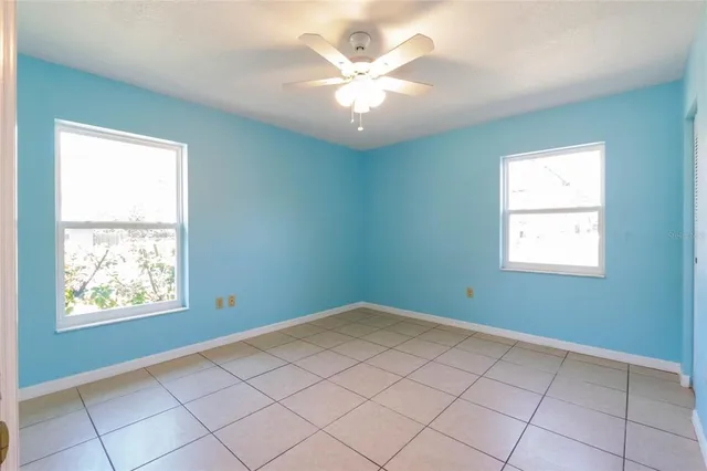 an empty room with windows and ceiling fan