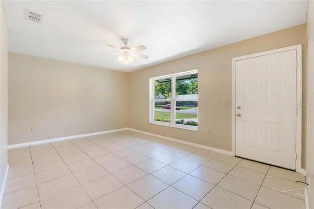an empty room with windows and fan