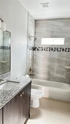 a bathroom with a granite countertop sink a toilet and bathtub