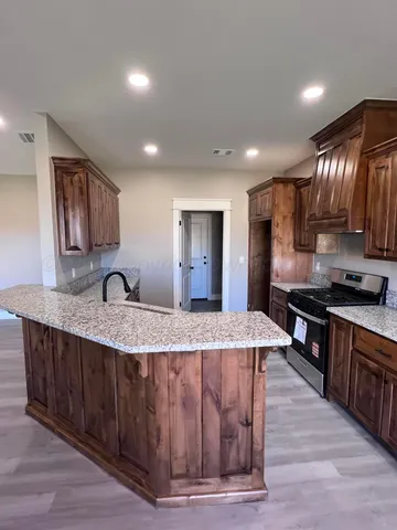 a large kitchen with granite countertop a large counter top a sink and stainless steel appliances