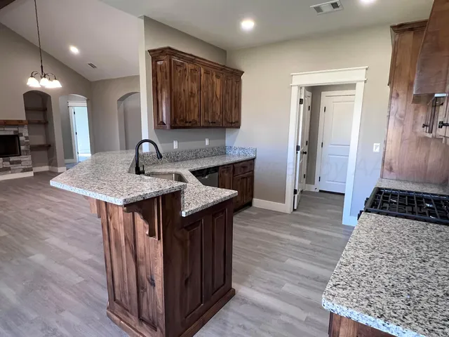a kitchen with granite countertop a stove and a wooden floor