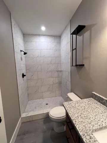 a bathroom with a granite countertop sink toilet and shower